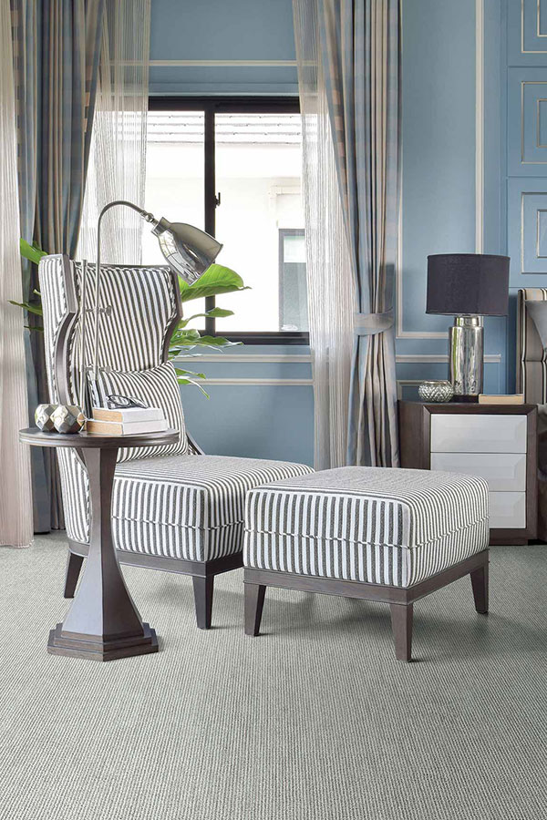 Living room painted blue with white trim and blue and white high back lounge chair with ottoman. 